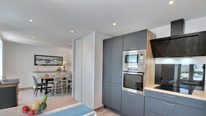 Eine moderne Küche mit grauen Schränken, einem eingebauten Backofen, einer Mikrowelle und einer schwarzen Induktionskochplatte.