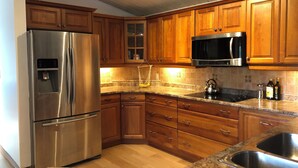 A kitchen with wooden cabinets, stainless steel appliances, granite countertops, and a double sink.