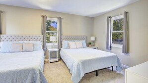Un dormitorio con dos camas, una ventana y una mesita de noche con lámpara.