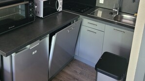 A compact kitchen with a microwave, toaster, and coffee maker on the counter, a sink, and stainless steel cabinets.