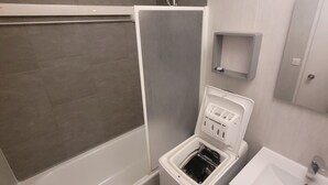 A modern bathroom with a bathtub, a built-in washing machine, and a sink.