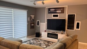 Una sala de estar con un televisor de pantalla plana grande, dos sofás, una mesa de centro y un tapete estampado.