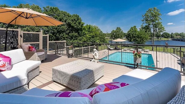 Una terraza con mobiliario exterior, una piscina y vistas a un lago.