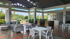 A spacious outdoor patio with a dining area, seating arrangements, and a bar. - Villa Haven Giovanni (Vega Alta)