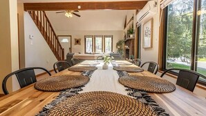 A dining room with a long wooden table, black chairs, and woven placemats.