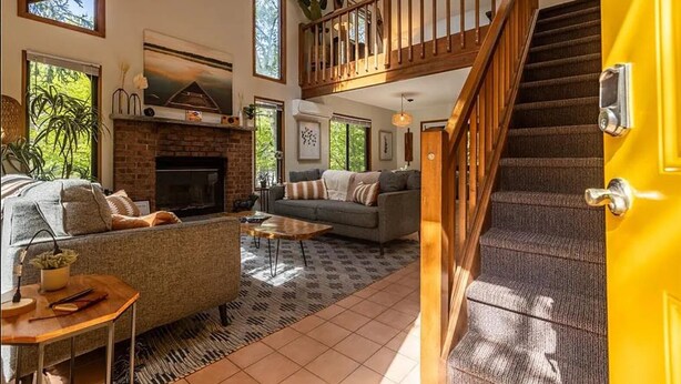 A spacious living area with a fireplace, a sofa, a coffee table, and a staircase leading to an upper level.