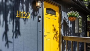 A building with a yellow door labeled "1139" and a hanging flower basket.