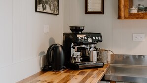 A kitchen with a coffee machine, a kettle, and a framed menu on the wall. - 4 Bedroom House - 1 Night (Wakefield)