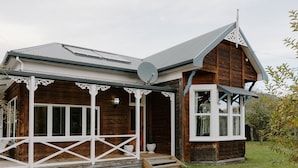 A wooden house with a porch, a satellite dish, and a small garden. - 4 Bedroom House - 1 Night (Wakefield)