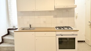 Keittiössä on pesuallas, liesi, uuni ja valkoiset kaapit.