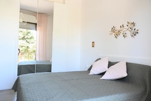 Ein Schlafzimmer mit einem Bett, einem Fenster mit Vorhängen und einem Wanddekor.