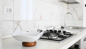 Eine Küche mit Gaskochfeld, modernem Spülbecken und Marmor-Spritzschutz.