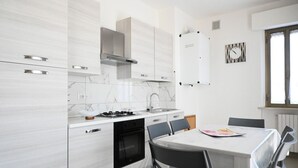Eine moderne Küche mit weißen Schränken, einem Gasherd und einem Essbereich mit Tisch und Stühlen.