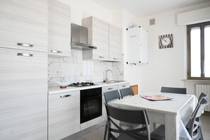 Eine moderne Küche mit weißen Schränken, einem Gasherd und einem Essbereich mit Tisch und Stühlen.