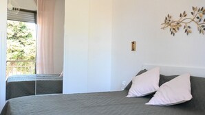 Ein Schlafzimmer mit einem Bett, zwei Kissen, einem Fenster mit Blick und einer Wanddekoration.