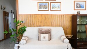 A room with a wooden paneled wall, a sofa with patterned cushions, a potted plant, and framed pictures on the wall. - PP06 - Porto Potenza, comfortable three-room apartment a few steps from the sea (Porto Potenza Picena)