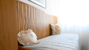 A bedroom with a wooden headboard, a bed with a white quilt, and a pillow with 'CASA VACANÇA' text. - PP06 - Porto Potenza, comfortable three-room apartment a few steps from the sea (Porto Potenza Picena)