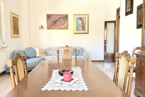 A dining area with a wooden table, chairs, and a lace table runner. - P061 – Porto Recanati, spacious and comfortable four-room apartment (Porto Recanati)
