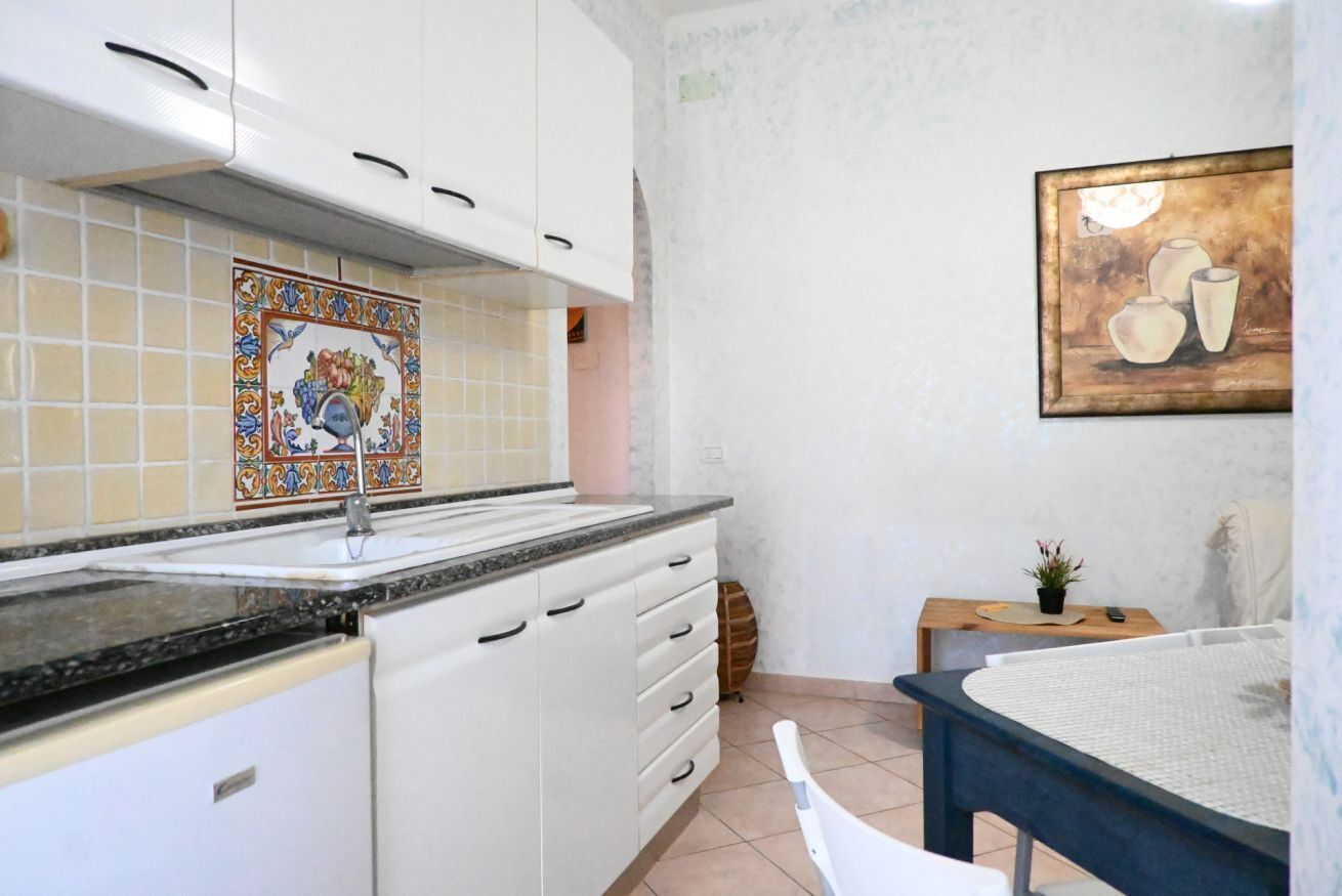 A kitchen with white cabinets, a tiled backsplash, and a painting on the wall.