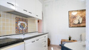 A kitchen with white cabinets, a tiled backsplash, and a painting on the wall. - S350 - Sirolo, comfortable three-room apartment in the center (Sirolo)