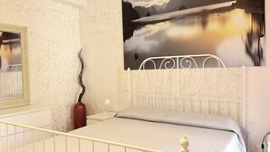 A bedroom with a bed, a nightstand, a vase, and a painting of a lake. - S350 - Sirolo, comfortable three-room apartment in the center (Sirolo)
