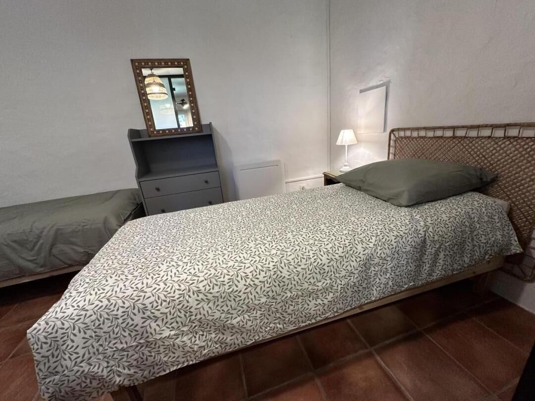 A bedroom with a bed, a nightstand, a dresser, and a mirror.