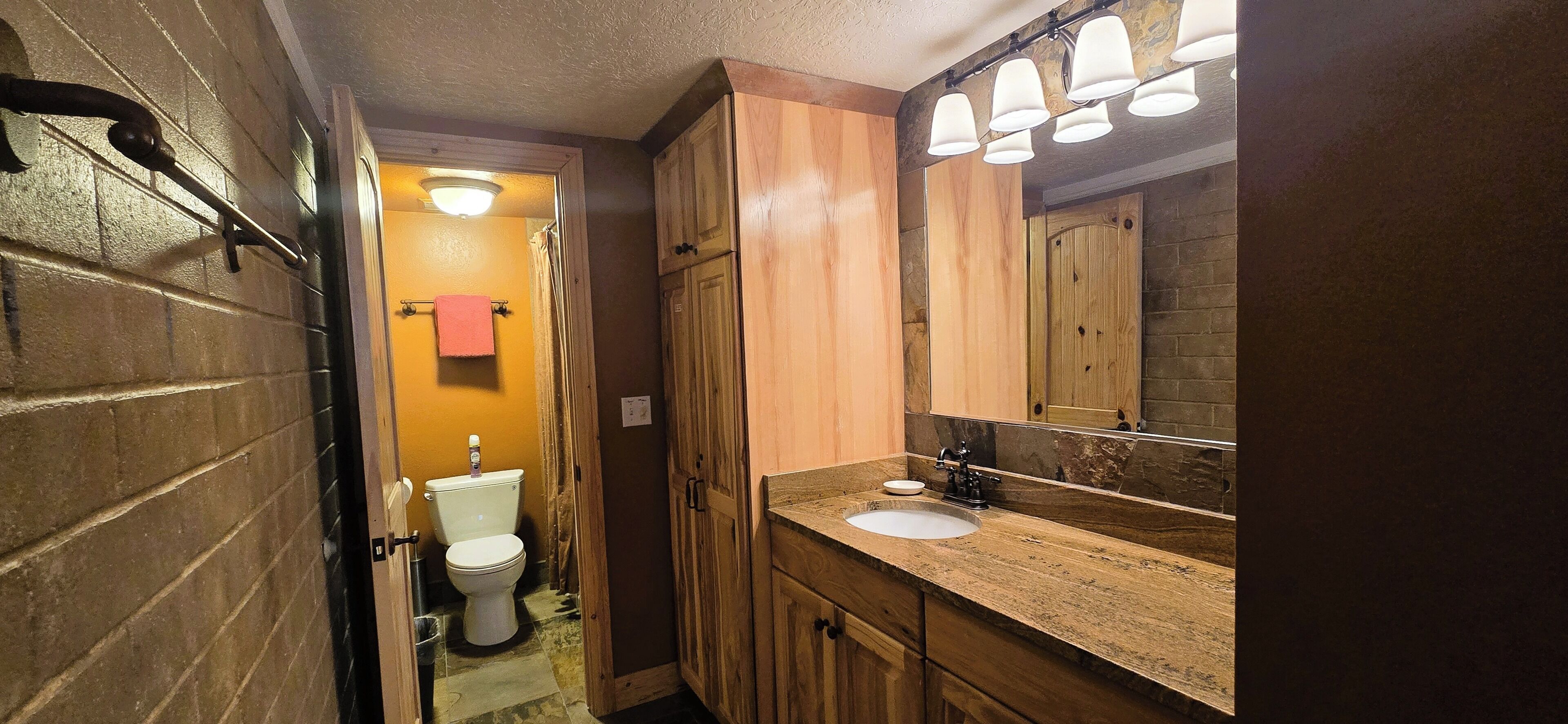 Une salle de bain avec un meuble-lavabo en bois, un lavabo blanc et un miroir avec éclairage intégré.