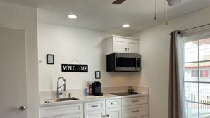Cocina moderna con armarios blancos, microondas integrado y un cartel que dice 'WELCOME'.