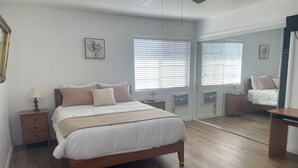 Un dormitorio con cama, mesitas de noche, un espejo y un ventilador de techo.