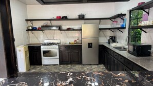 Eine moderne Küche mit Gasherd, Backofen, Kühlschrank und einer schwarzen Arbeitsplatte.