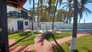 Un patio trasero con piscina, palmeras y un sendero.