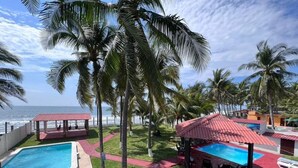 Un resort con piscina, palmeras y vista al mar.