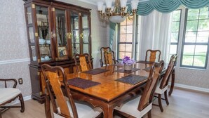 A dining room with a wooden table and chairs, a china cabinet, and a chandelier.