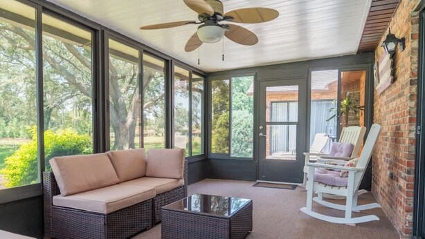 A sunroom with a sofa, chairs, and a coffee table.
