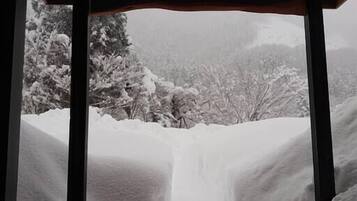 A snow-covered landscape viewed through a wooden structure with a light source above.