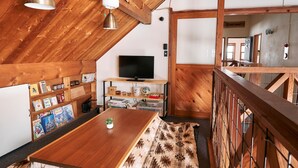 Un interior acogedor de madera con techo alto, una mesa de comedor de madera y una alfombra estampada.