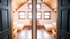 Reflejo de una habitación con dos camas, una silla y una ventana.