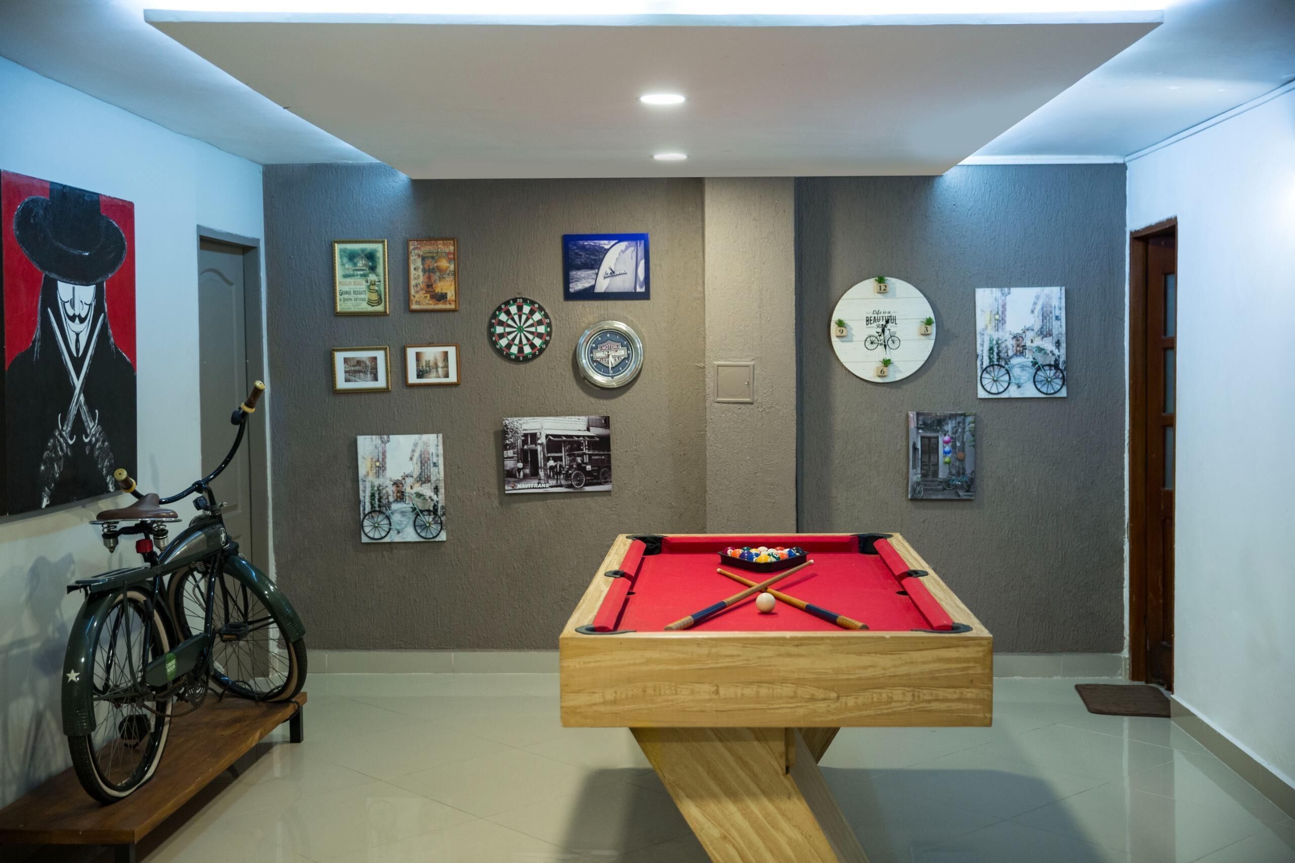A room with a pool table, a bicycle, and various framed pictures on the walls.