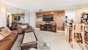 A spacious living room with a brown leather sofa, a coffee table, and a television. - Charming 1-bedroom condo in delightful Pompano Beach with WiFi, AC (Pompano Beach)