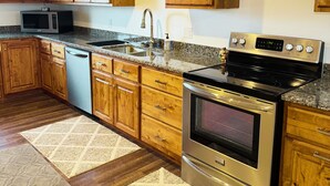 A kitchen with wooden cabinets, a stainless steel stove, a microwave, and a dishwasher.