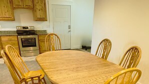 A dining room with a large wooden table and six chairs.