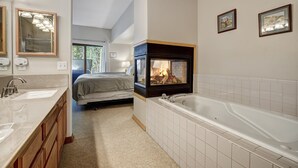 Un baño moderno con una bañera grande, un tocador con lavamanos doble y una chimenea.