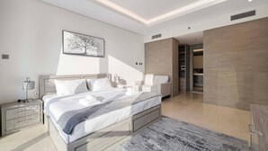 Ein modernes Schlafzimmer mit einem großen Bett, Nachttischen, einer Wandlampe und einer Deckenleuchte.