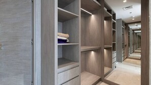 Ein moderner begehbarer Kleiderschrank mit mehreren Regalen und Schubladen, einer Spiegelwand und einem glänzenden Boden.