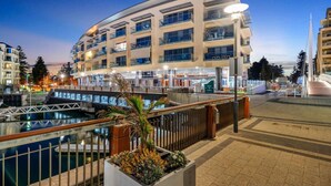 A modern hotel with multiple floors, a waterfront view, and a pedestrian bridge.