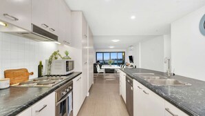A modern kitchen with white cabinets, a black countertop, and a view to the dining area.