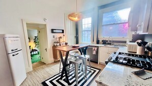 A modern kitchen with a refrigerator, stove, and bar stools.
