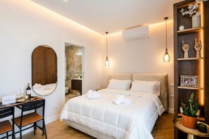 Habitación de hotel con cama, mesita de noche, espejo y estante con adornos.