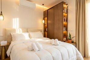 Habitación de hotel con una cama grande, un armario de madera, una mesita de noche con una lámpara y una planta en maceta.