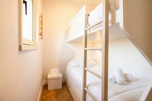 Habitació amb lliteres, una petita taula de nit i una finestra.